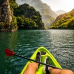 Person kayaking on the emerald waters of lake surrounded by towering cliffs near Skopje, North Macedonia.