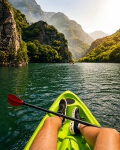 Person kayaking on the emerald waters of lake surrounded by towering cliffs near Skopje, North Macedonia.